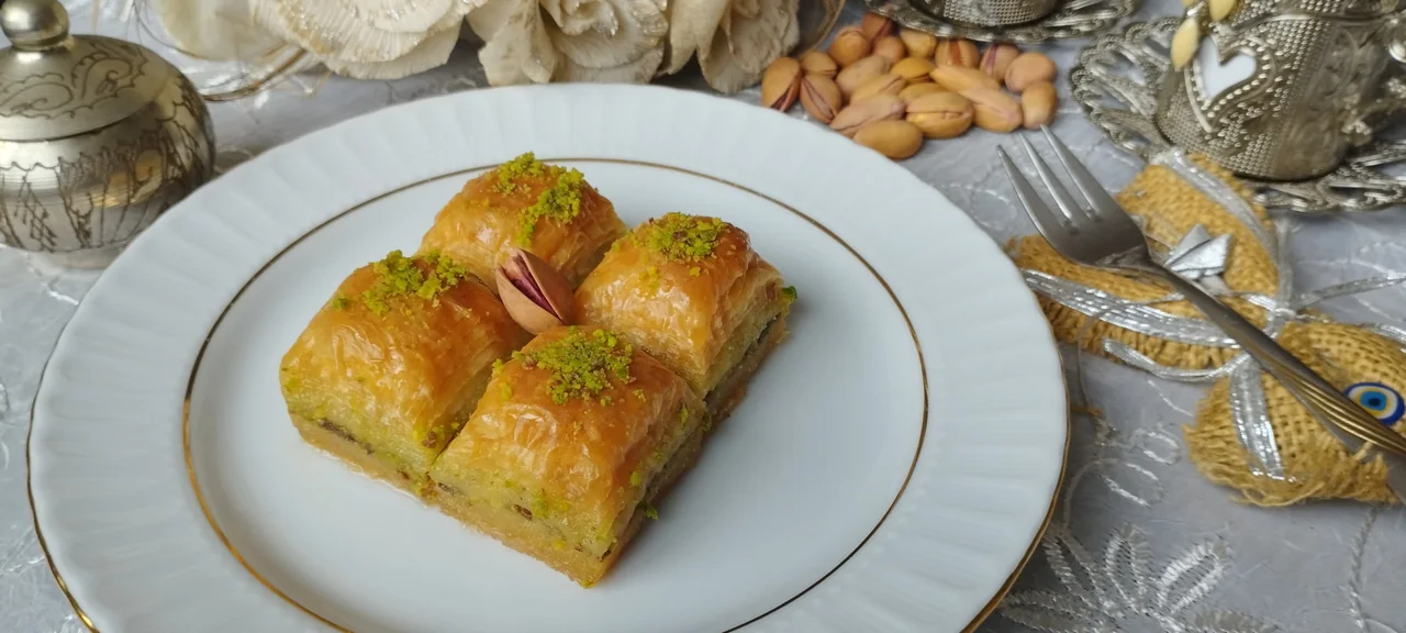Four pieces of pistachio baklava on a white plate