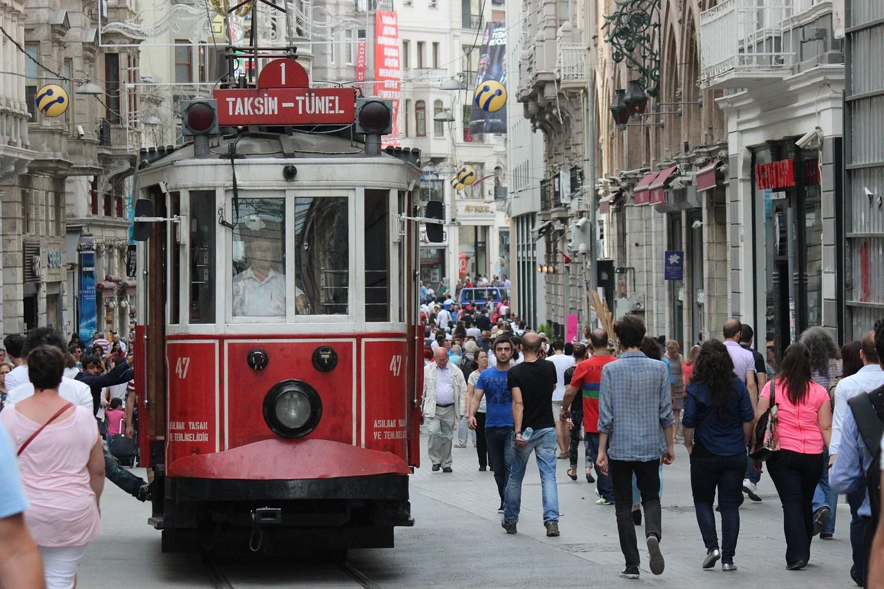 A red nostalgic tram among pedestrians on İstiklal Avenue