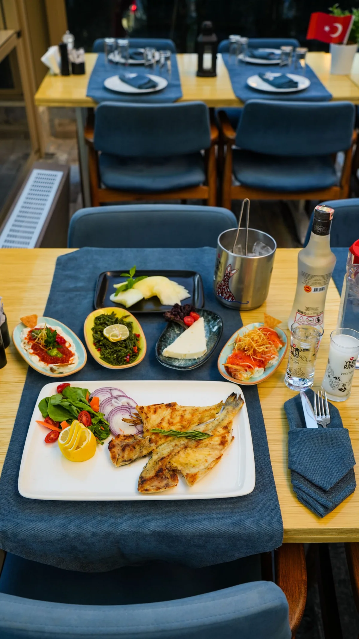 Grilled fish, meze plates and rakı set on a restaurant table