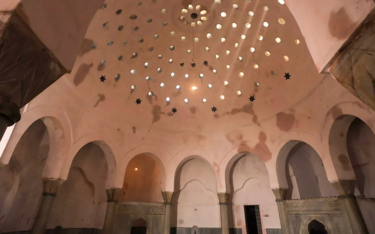 Marble walls and arches beneath the pink dome and star-shaped skylights of Cemberlitas Hammam
