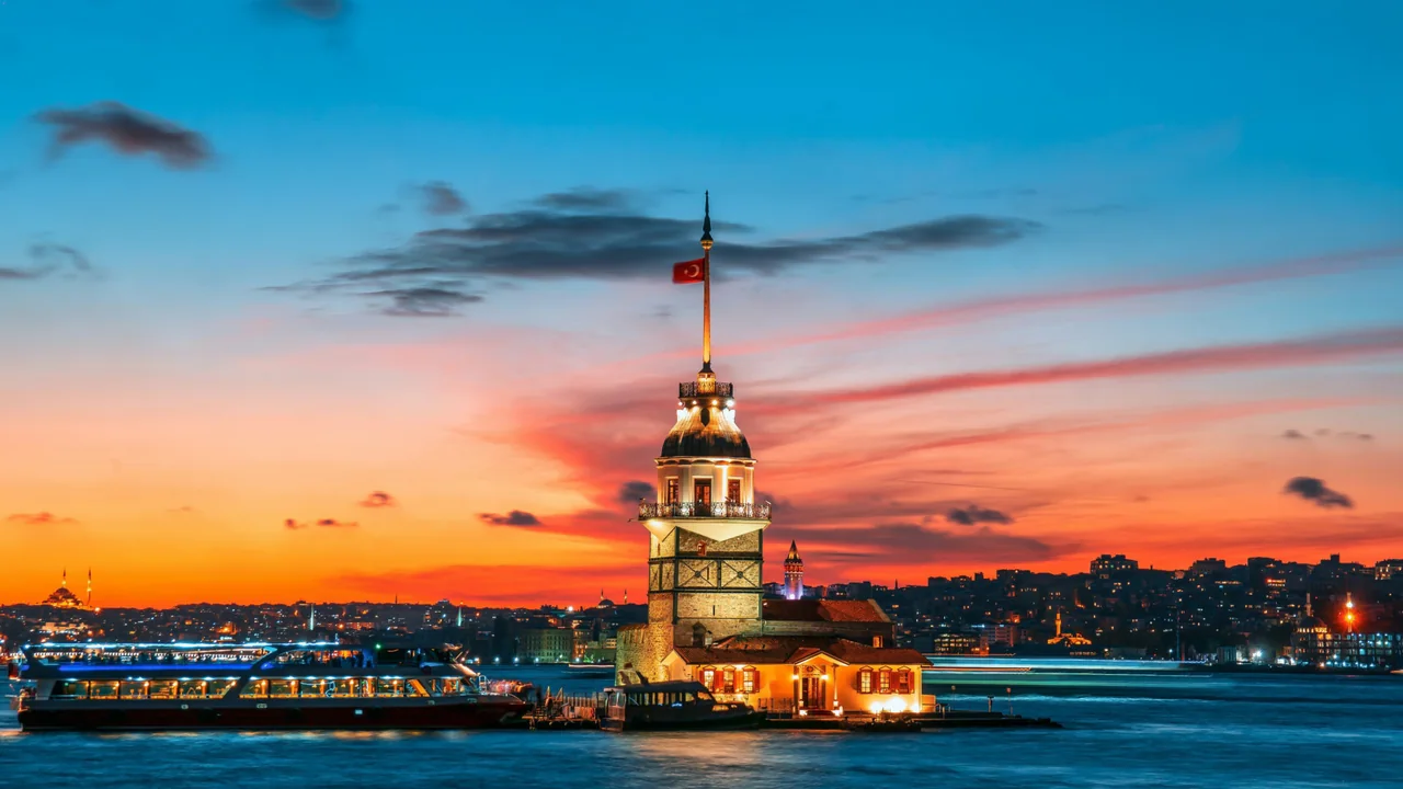 Illuminated Maiden’s Tower and a boat on the Bosphorus beneath a colourful evening sky