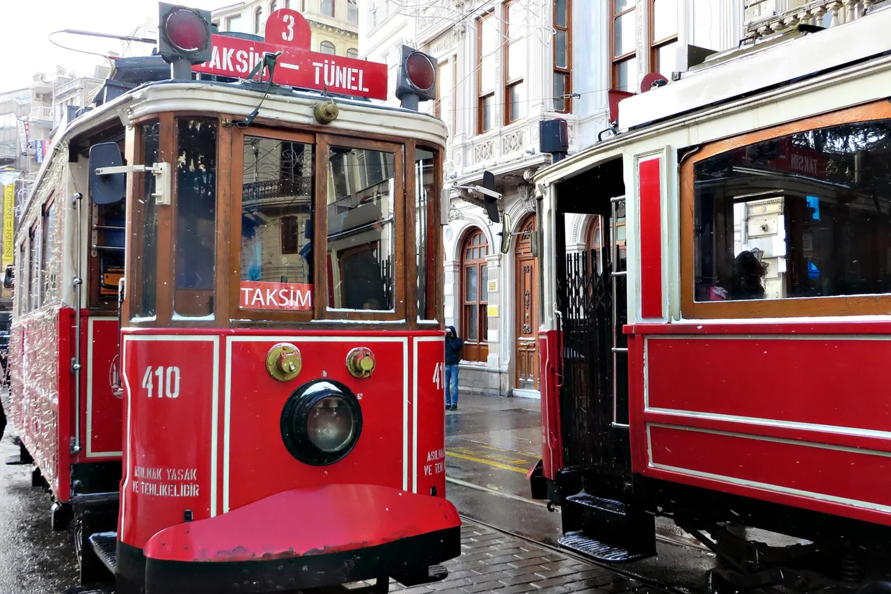 Two red nostalgic trams on İstiklal Avenue in daylight